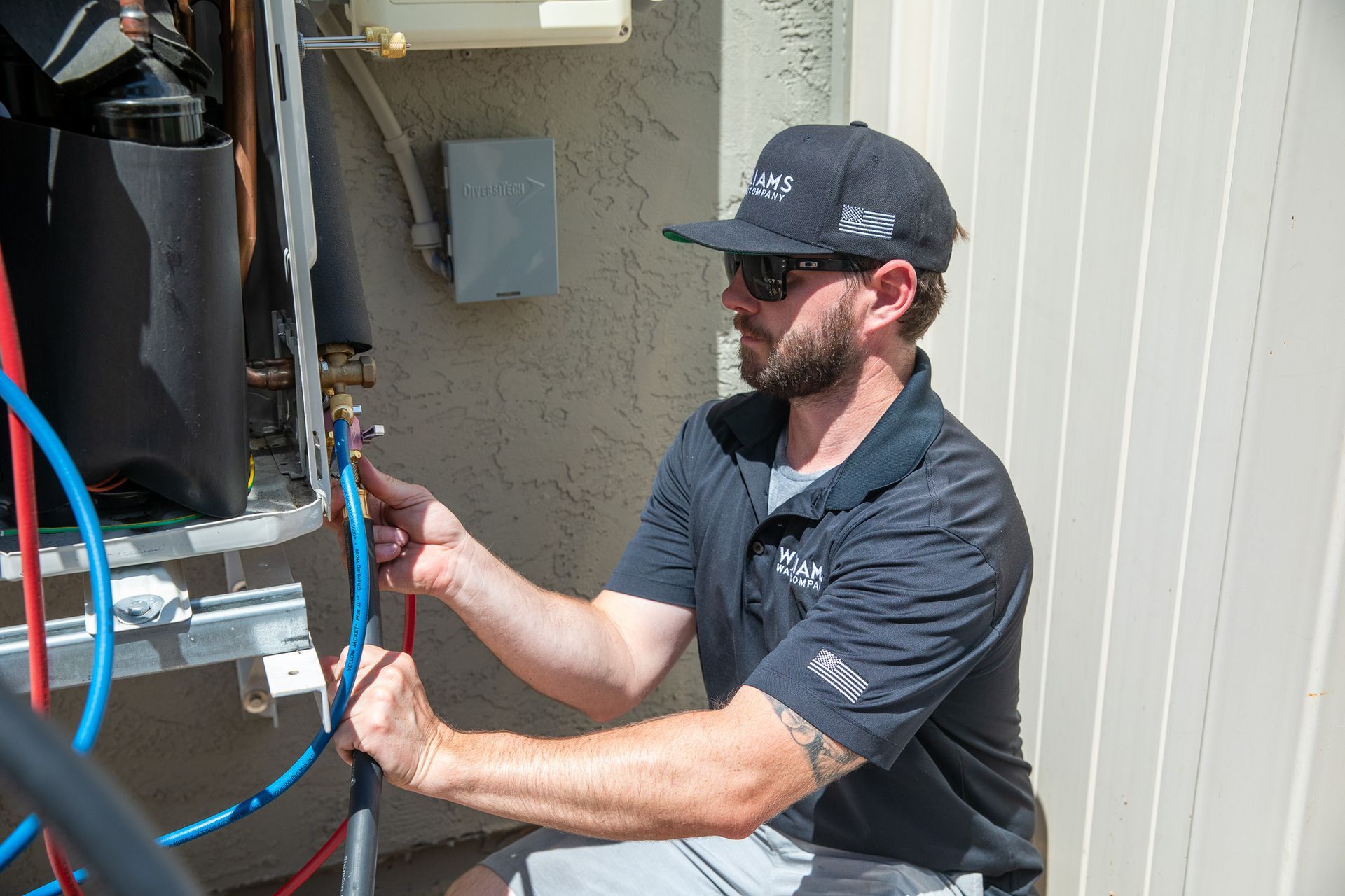 Williams Mechanical Co HVAC technician connecting refrigerant hoses to an outdoor unit