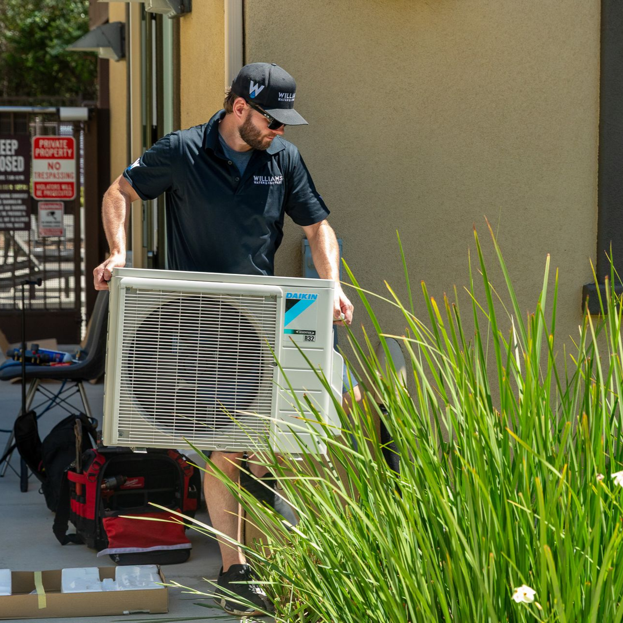 Williams Mechanical Co technician carrying a Daikin mini-split unit for installation