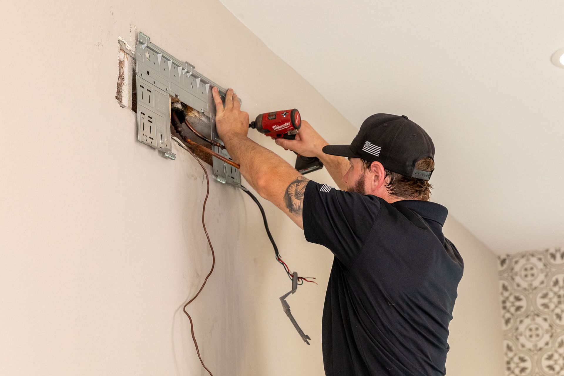 Williams Mechanical Co technician installing a mini-split unit on a wall in San Diego