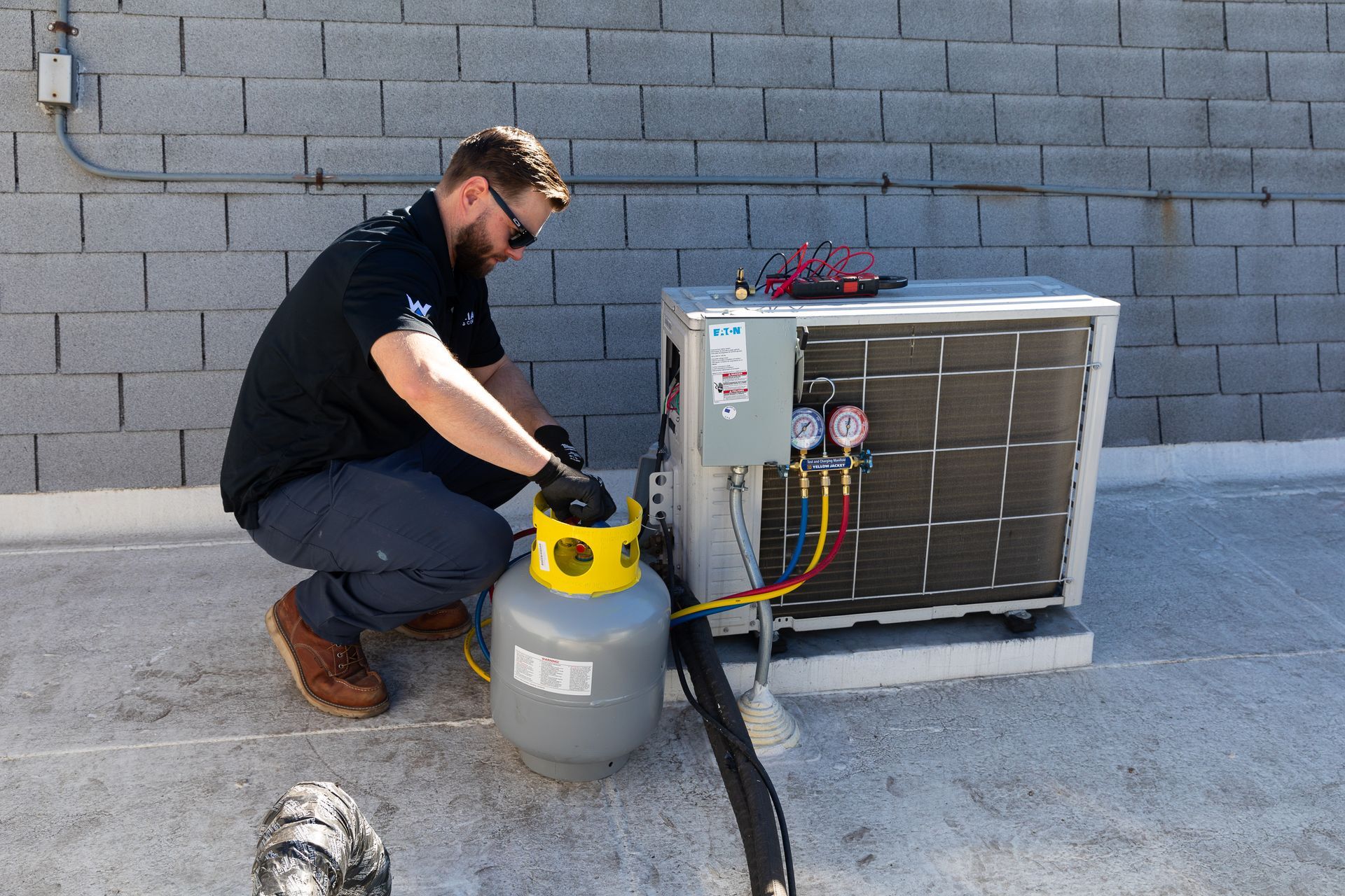 Williams Mechanical Co HVAC technician connecting a refrigerant tank to an AC unit
