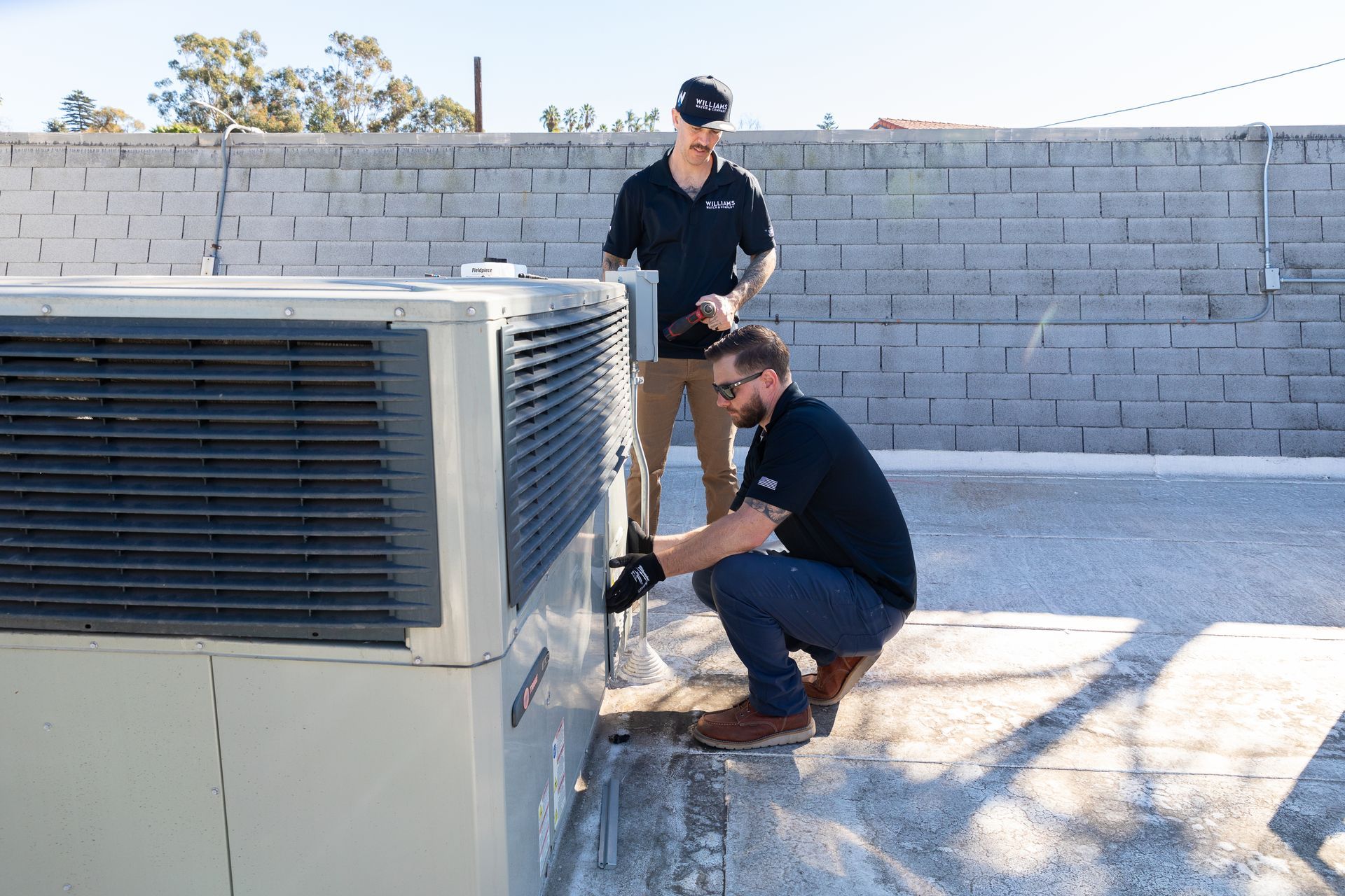 Williams Mechanical Co technicians inspecting a rooftop Trane HVAC unit