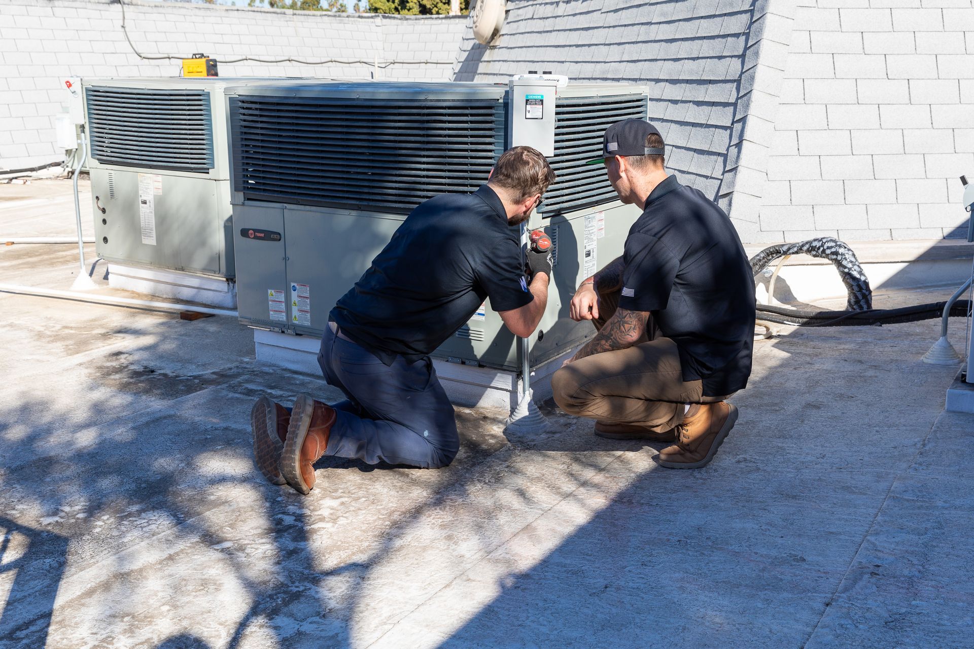 Williams Mechanical Co technicians inspecting a rooftop Trane HVAC unit in San Diego
