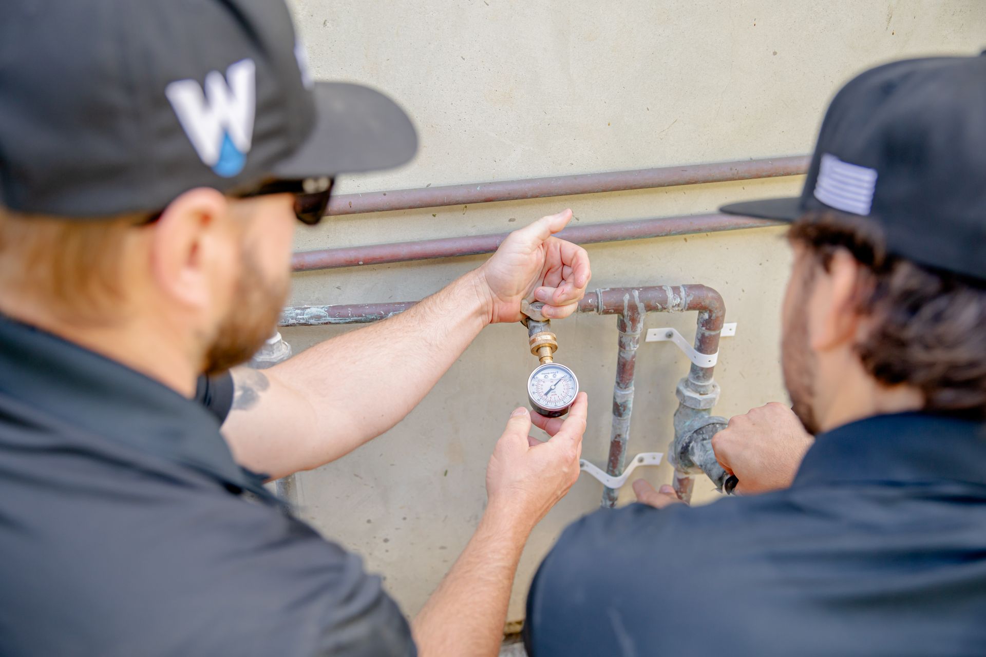 Williams Mechanical Co technicians inspecting a pressure gauge on a plumbing system