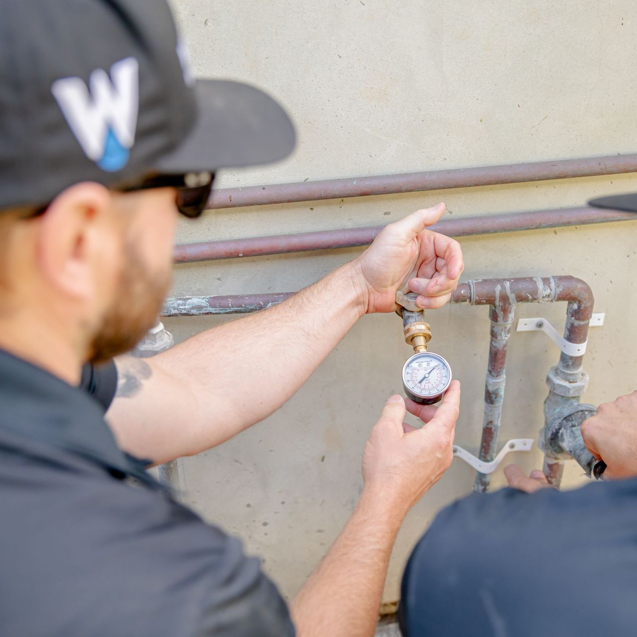 Williams Mechanical Co technician checking water pressure gauge on copper pipes