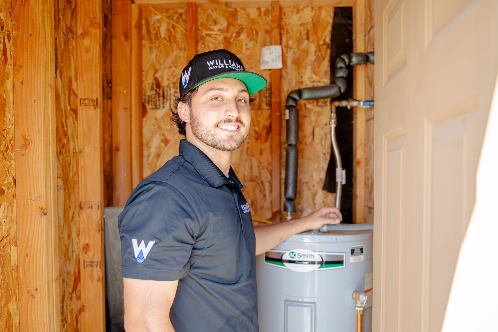 Williams Mechanical Co technician smiling next to a water heater installation