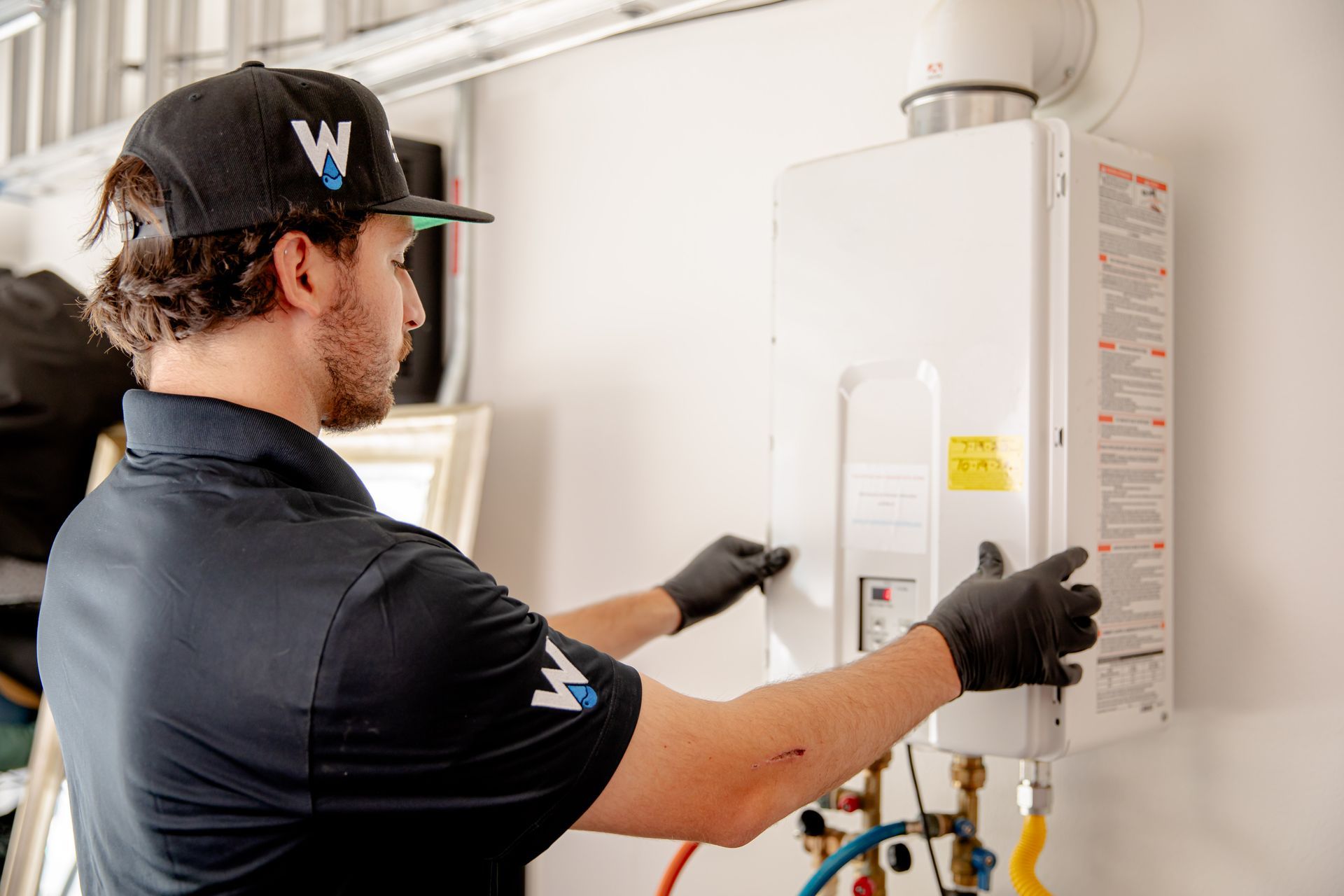 Williams Mechanical Co technician adjusting a tankless Rinnai water heater