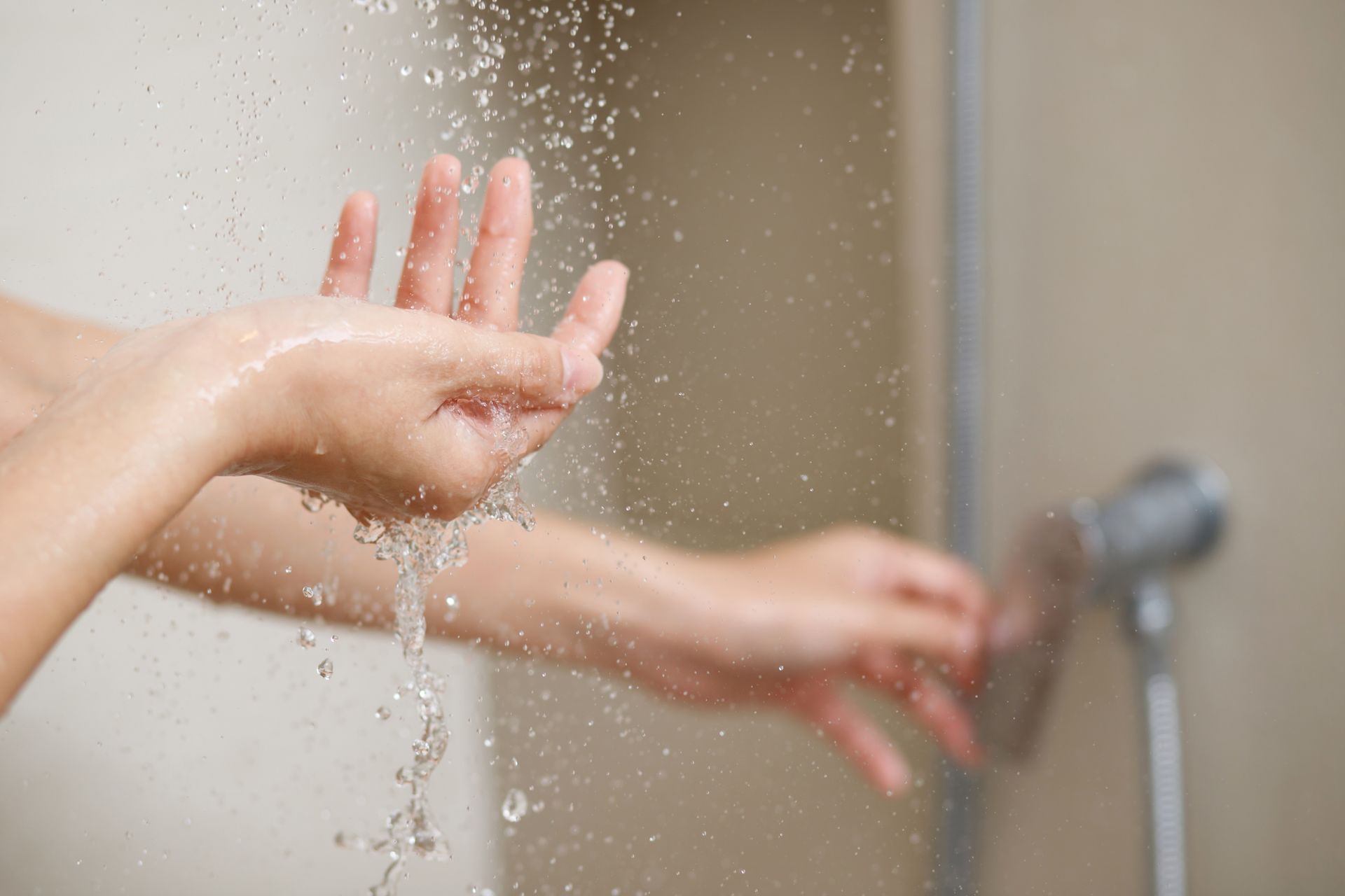 Person's hands reaching toward a shower, testing the water temperature.