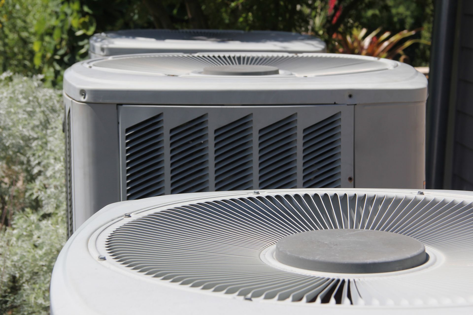 Close-up of three air conditioning units outdoors, with fan blades visible.