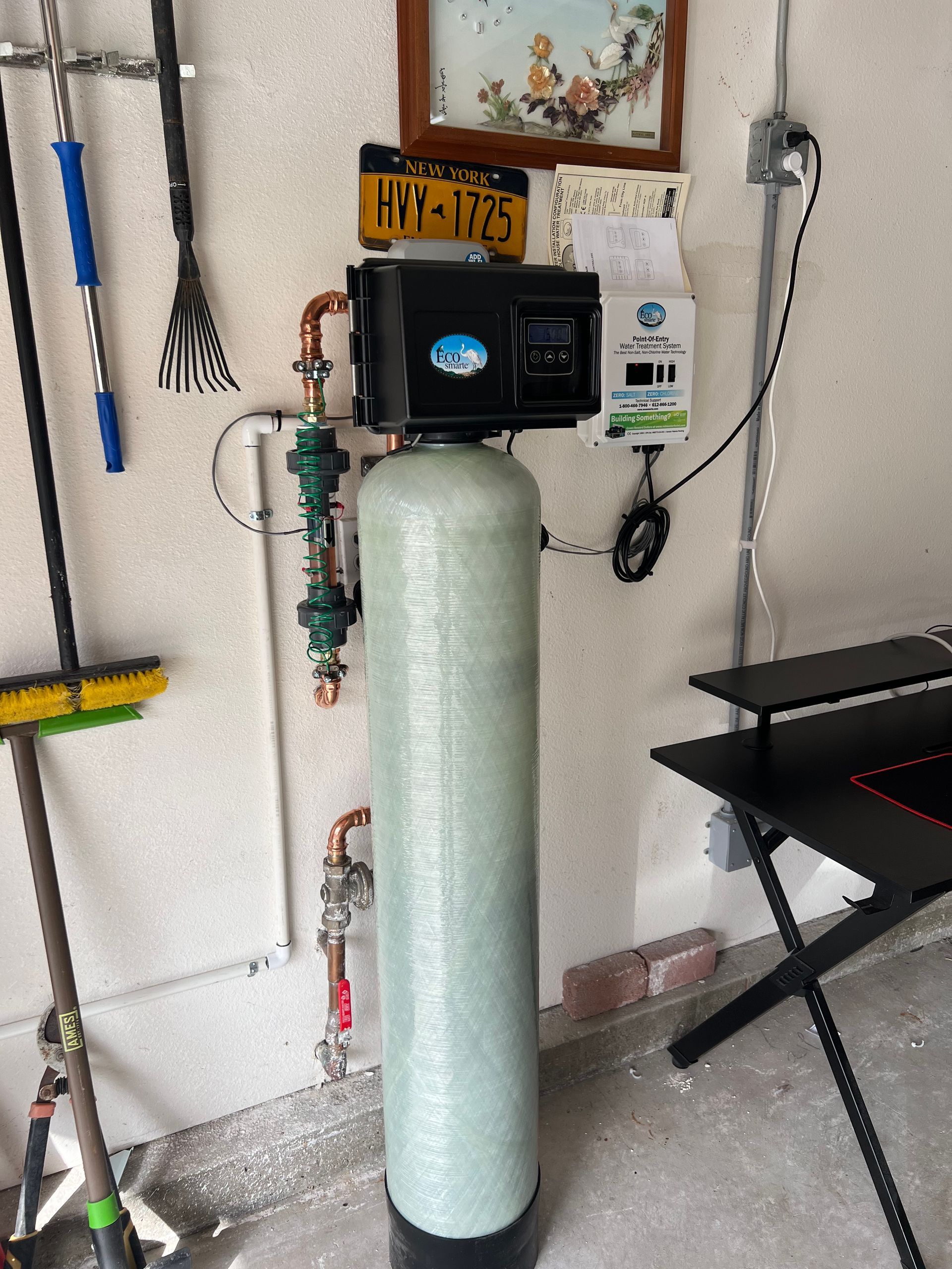 Water softener system in a garage setting with connected piping and electronic controls.
