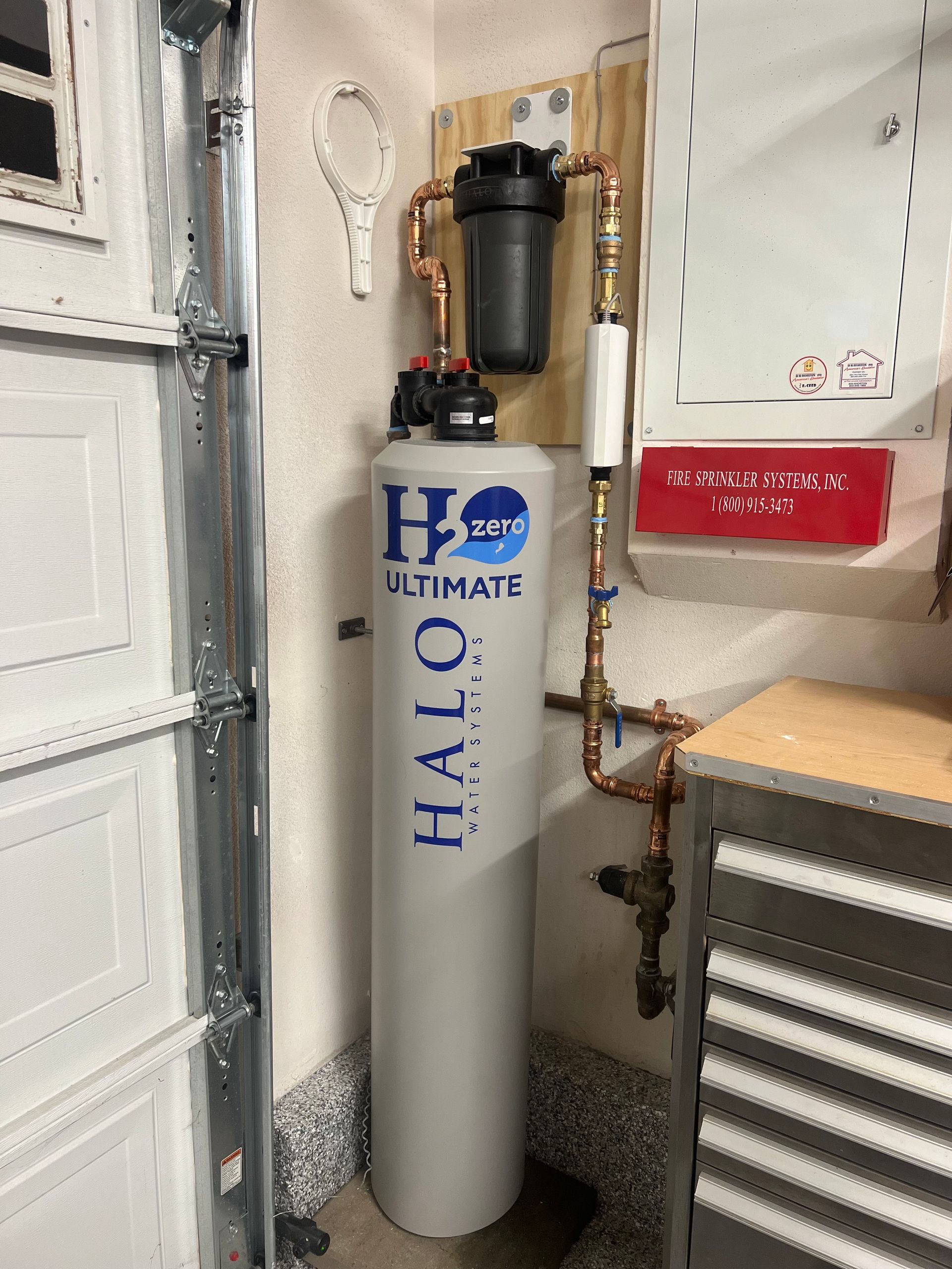 Halo Water filtration system installed in a garage, with copper pipes and a large tank.