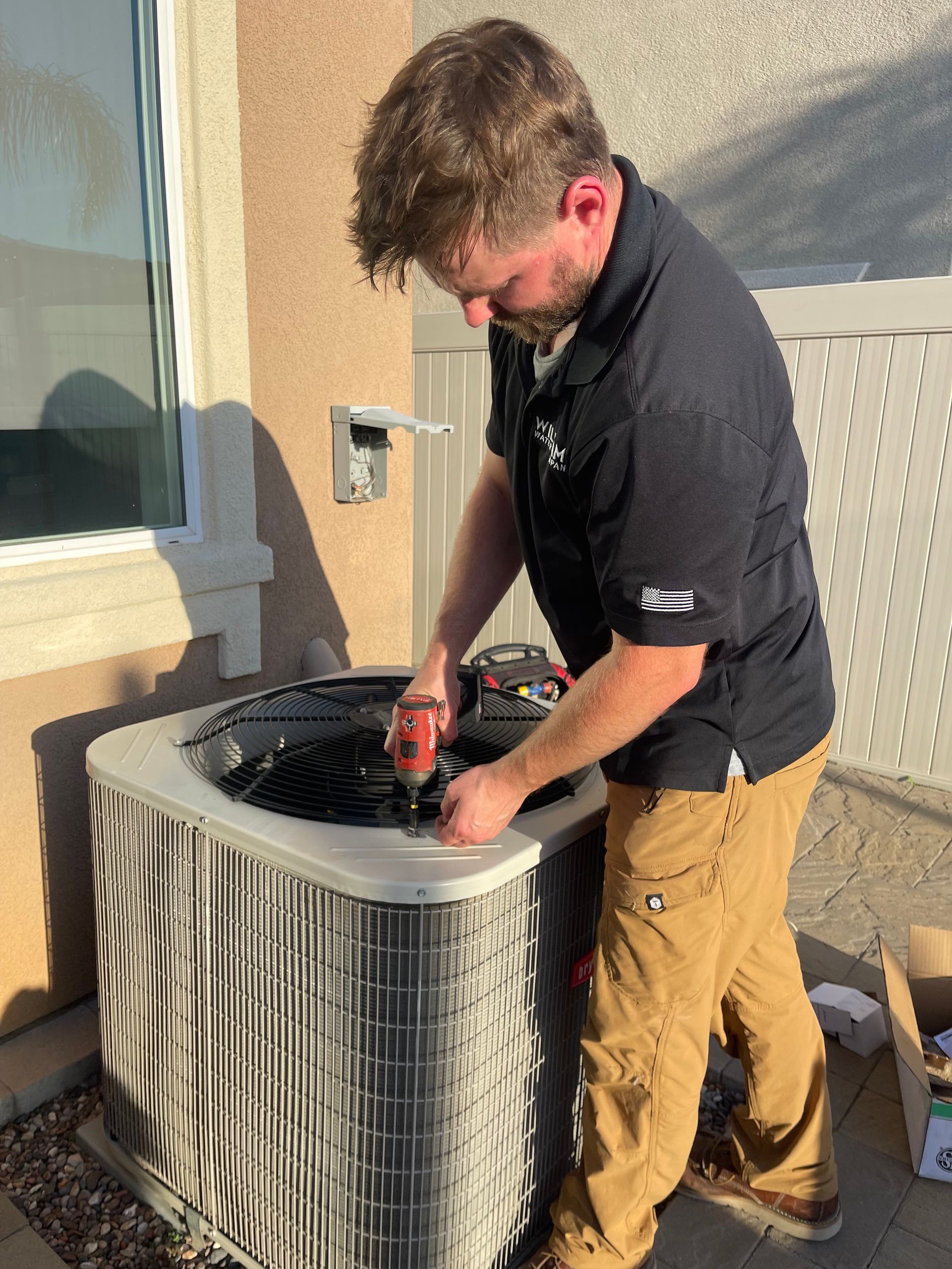 Williams Mechanical Co technician using a Milwaukee impact on an outdoor AC unit