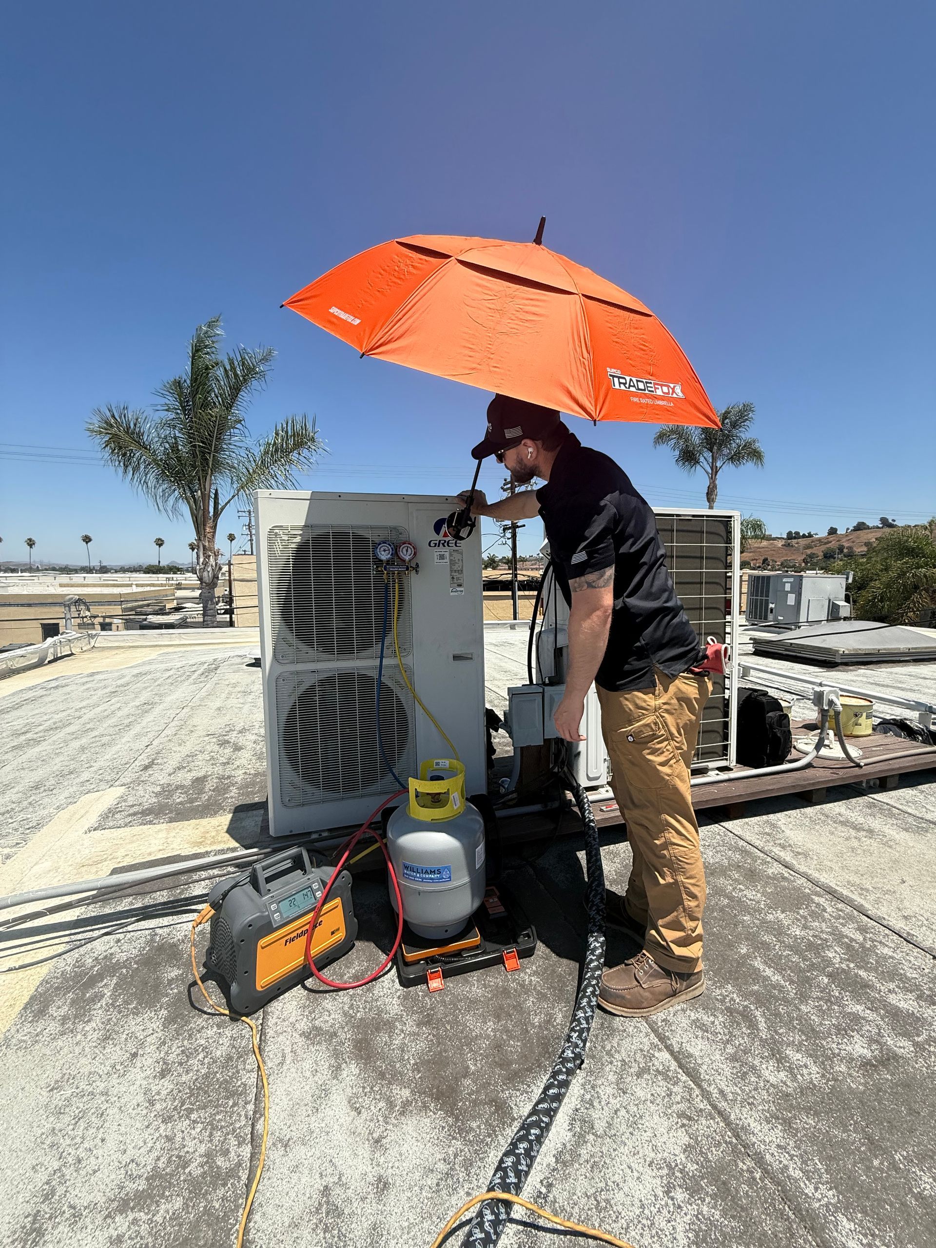 Williams Mechanical Co HVAC technician servicing a Gree rooftop unit in the Oceanside heat.