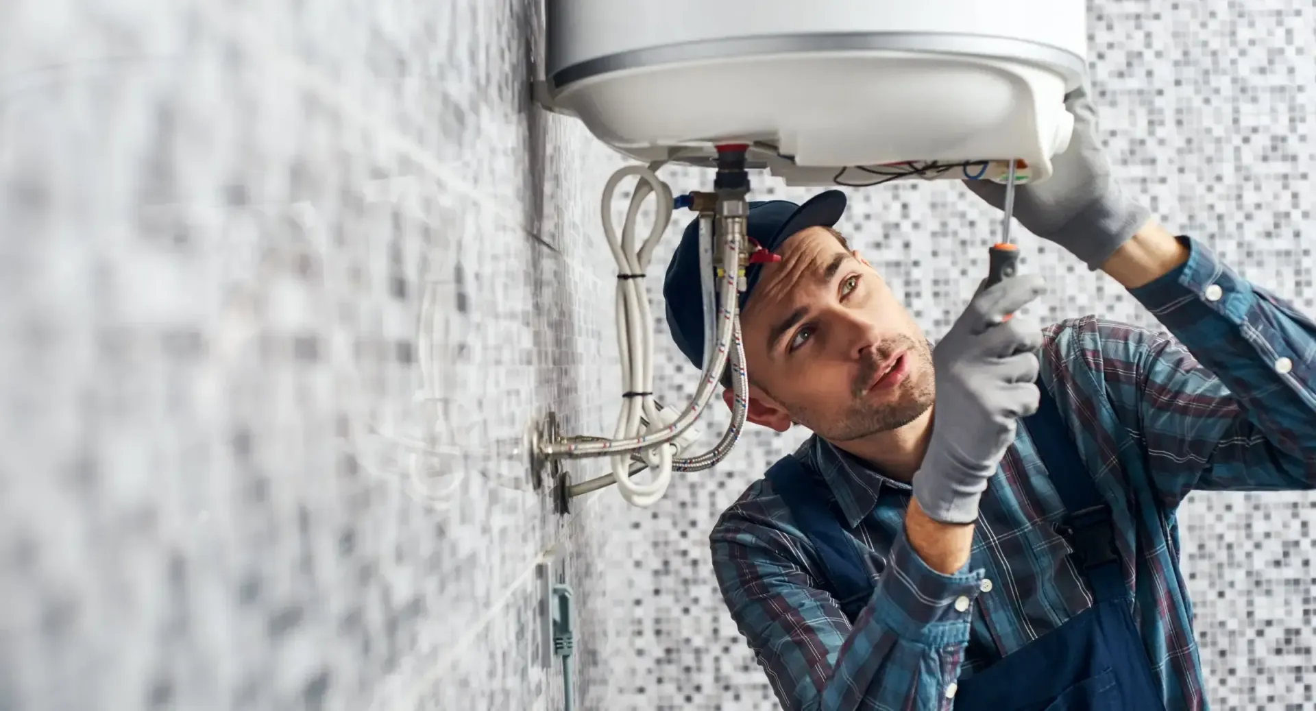 A man is fixing a water heater in a bathroom.