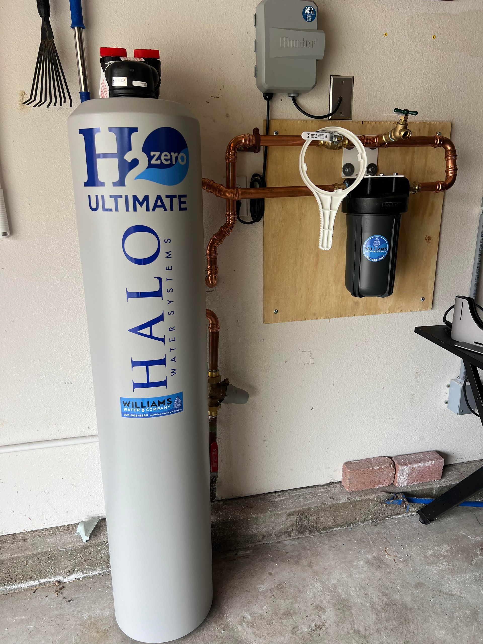 Water filtration system against a wall, including a large tank, filter, and piping.