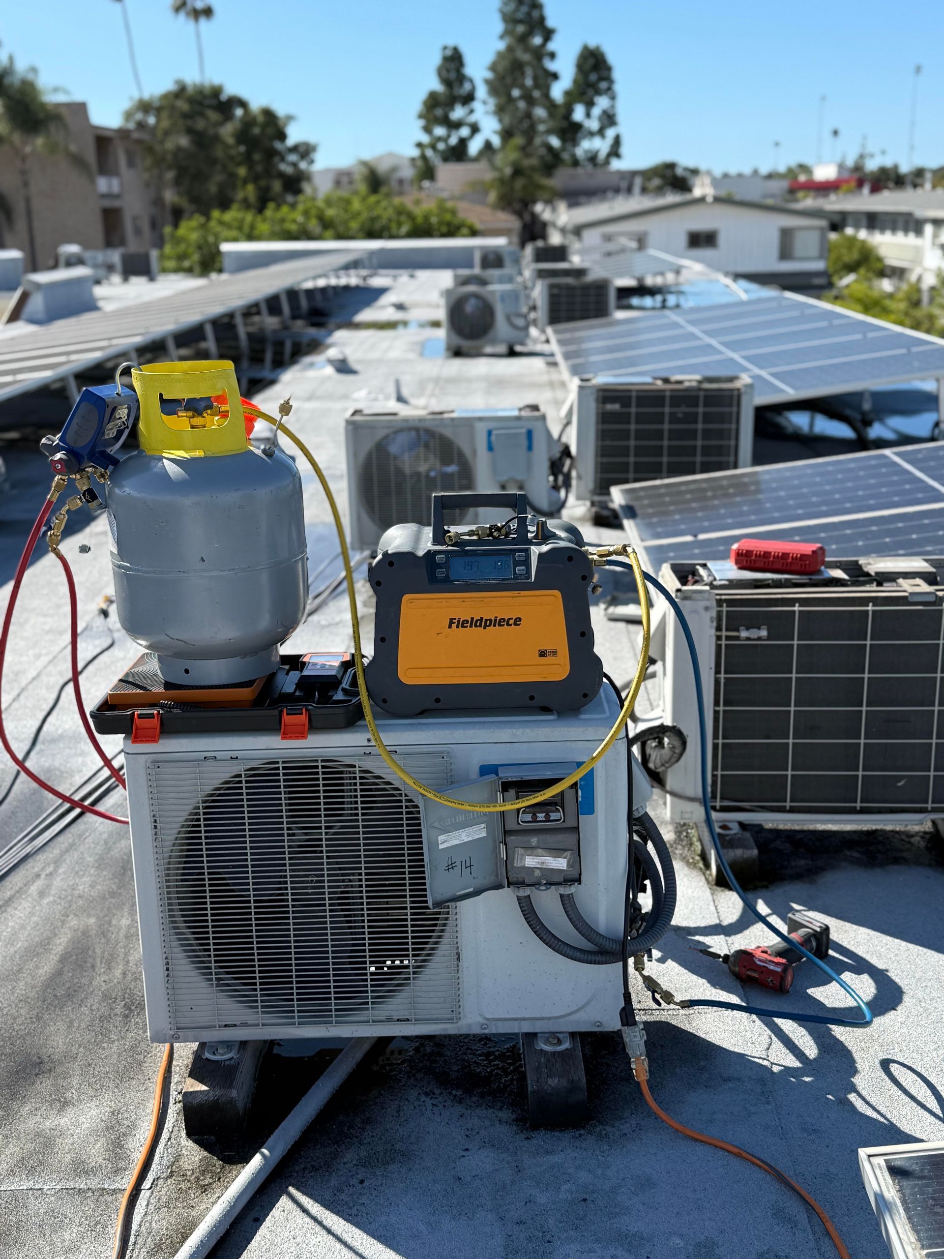 Williams Mechanical Co HVAC equipment setup on a apartment rooftop with Fieldpiece recovery tool and refrigerant tank.