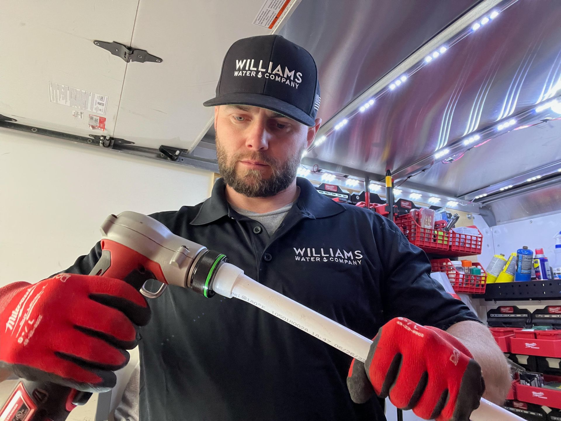 Williams Mechanical Co technician using a Milwaukee PEX-A pipe expander during a plumbing installation.