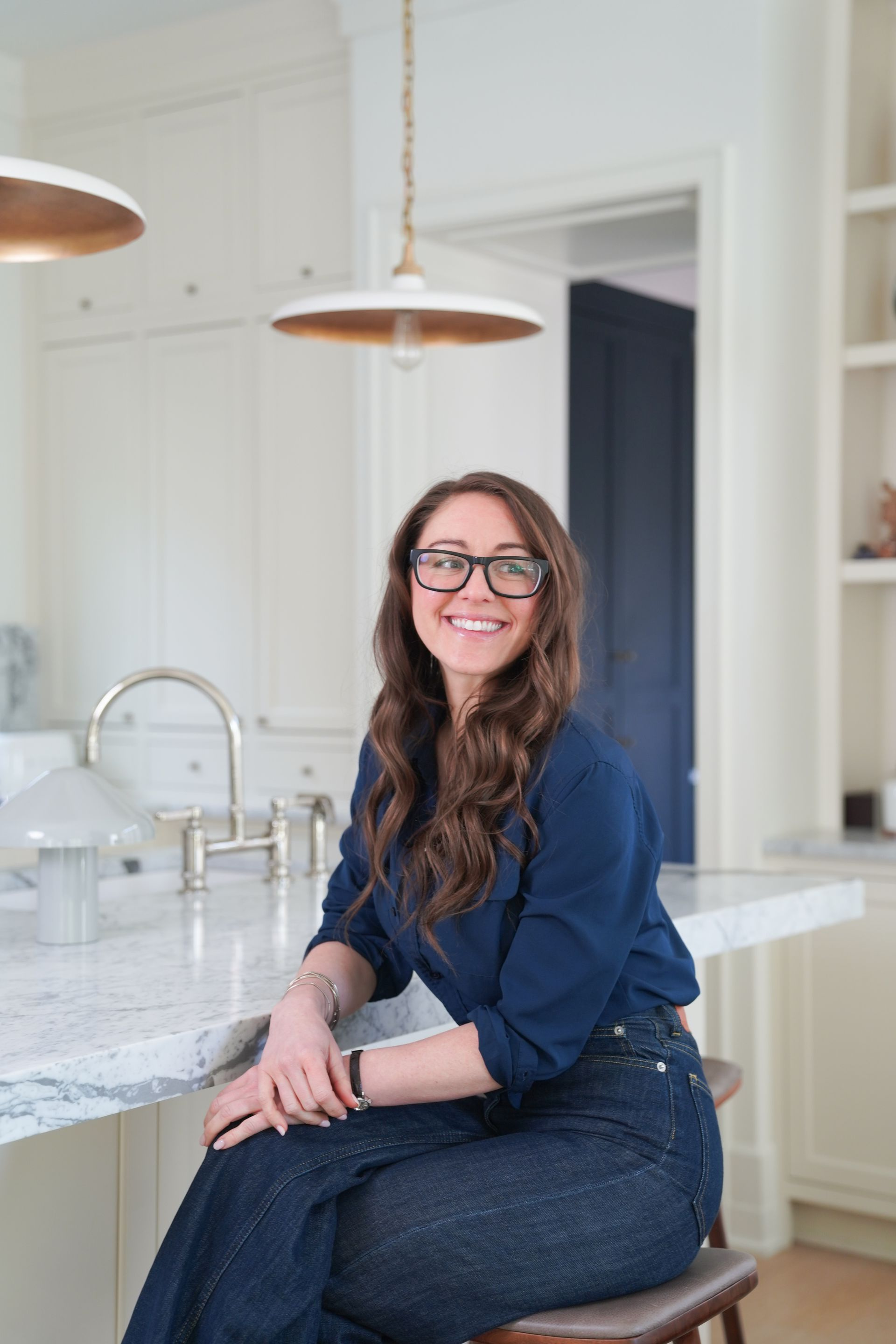 Woman smiling while seated on a kitchen island in a bright, modern kitchen