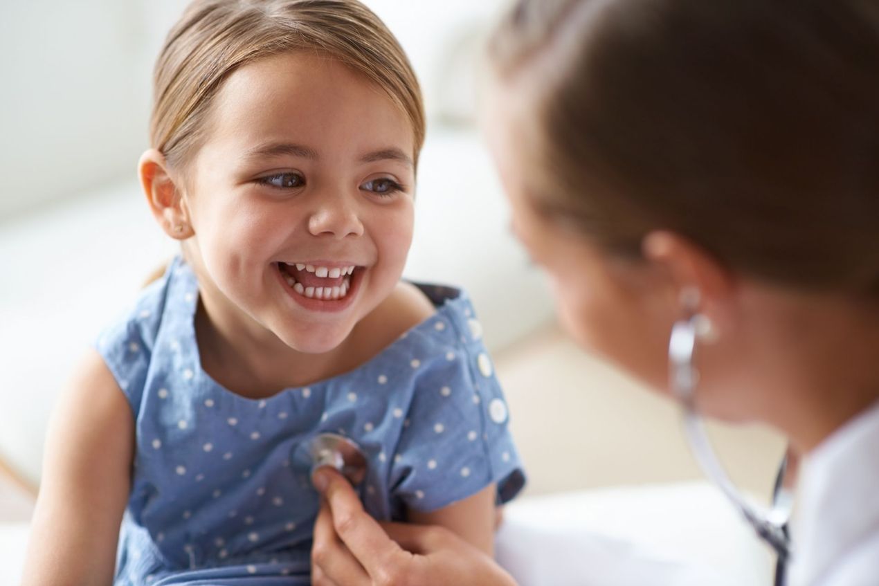 Smiling child in a blue shirt talking with a doctor during a checkup
