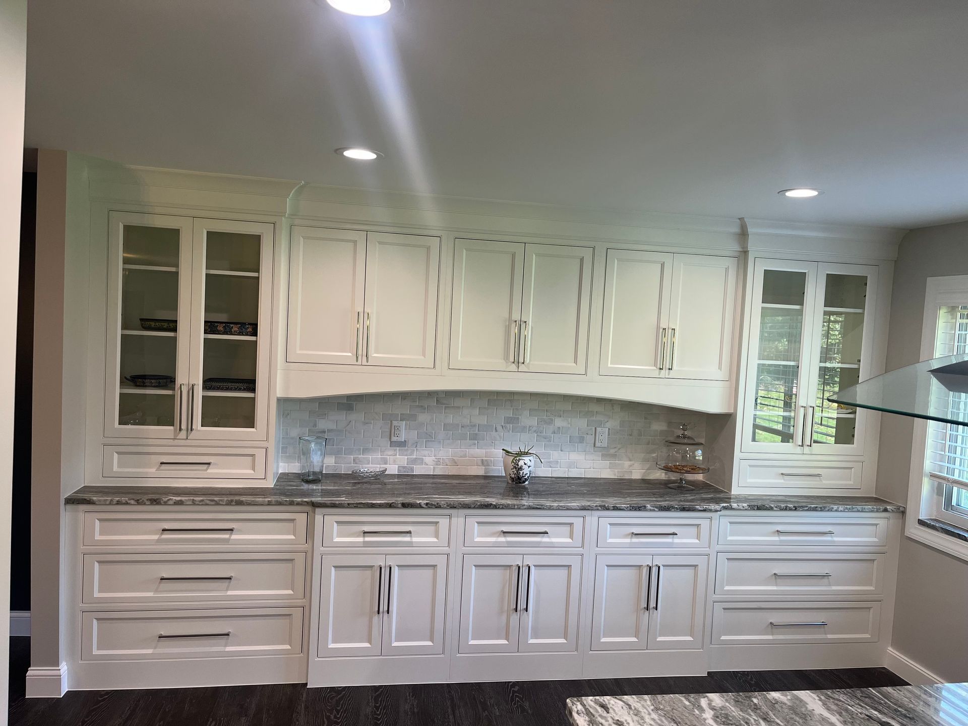 A kitchen with white cabinets and granite counter tops.