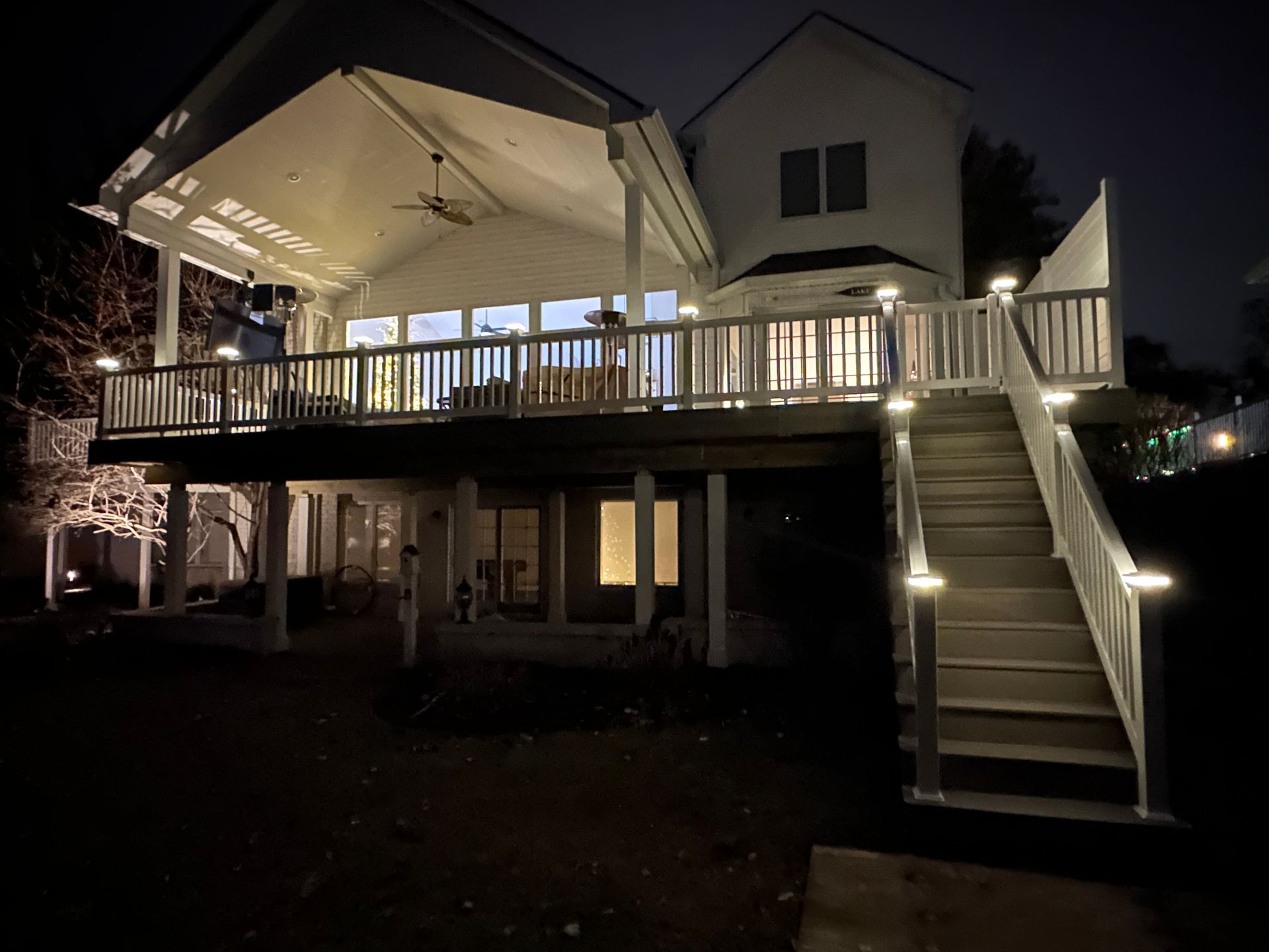 A house with a large deck and stairs at night