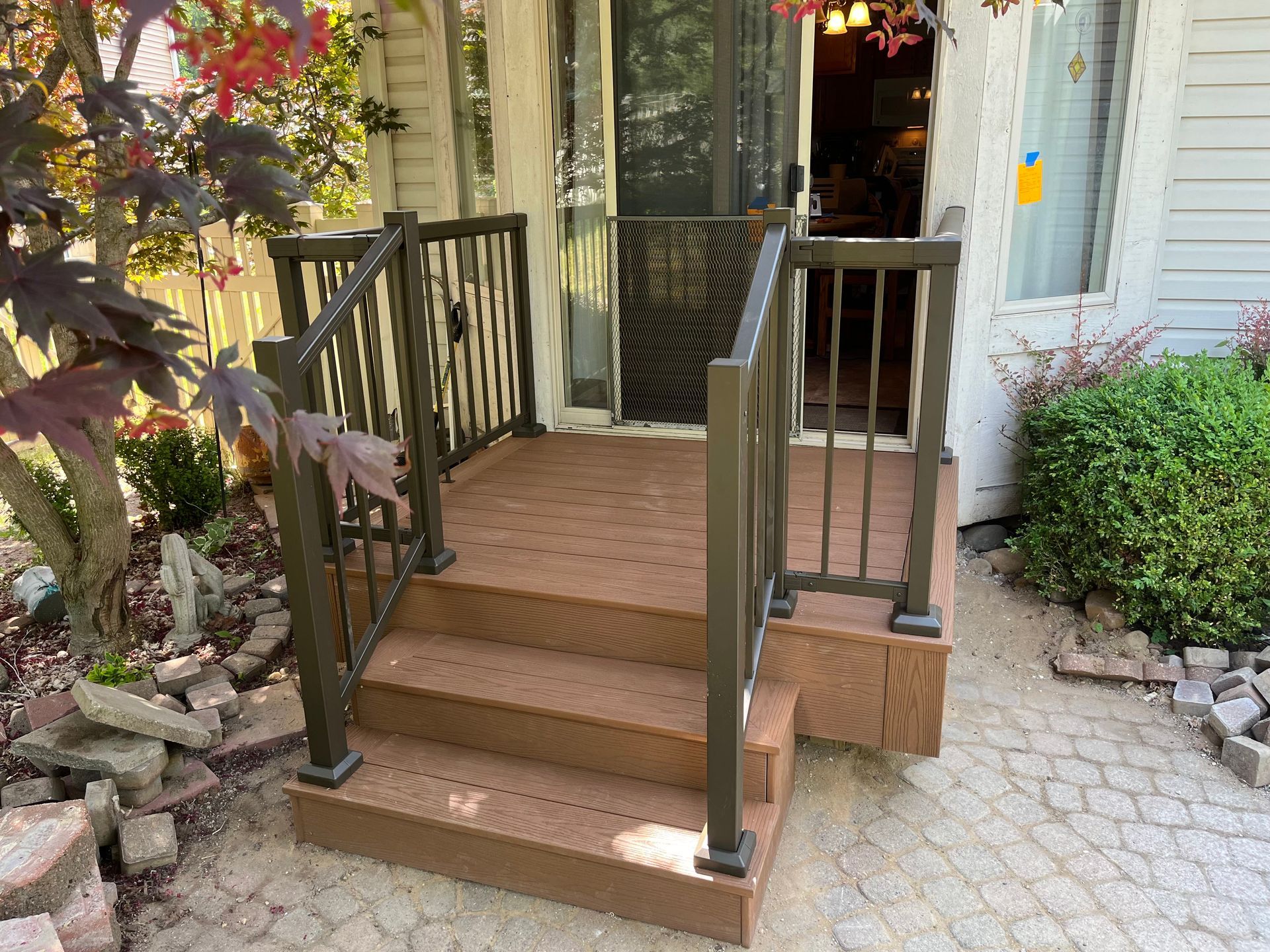 A wooden deck with stairs and a metal railing in front of a house.