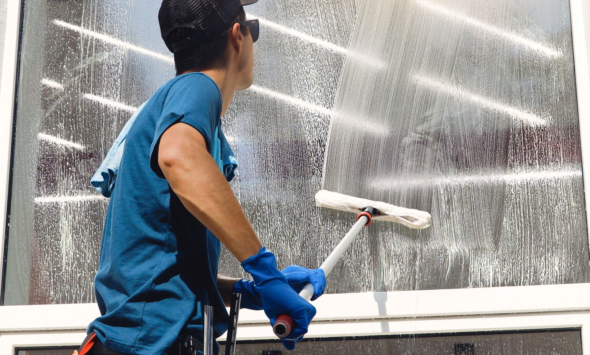 A professional cleaner using a squeegee for a window cleaning service on a large glass pane.