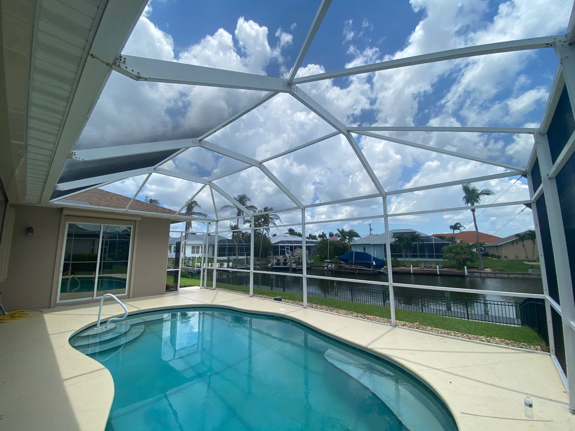A large swimming pool with a screened in area in front of a house.