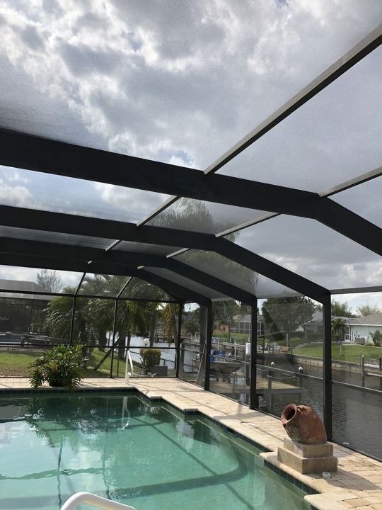A screened in swimming pool with a view of the water