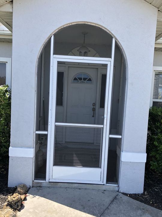 A white house with a screened in porch and a white door