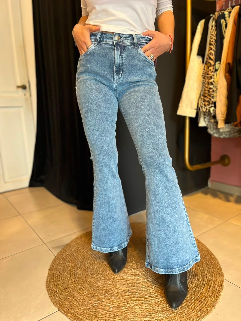 Persona con pantalones vaqueros azules acampanados y botas negras en una tienda de ropa.