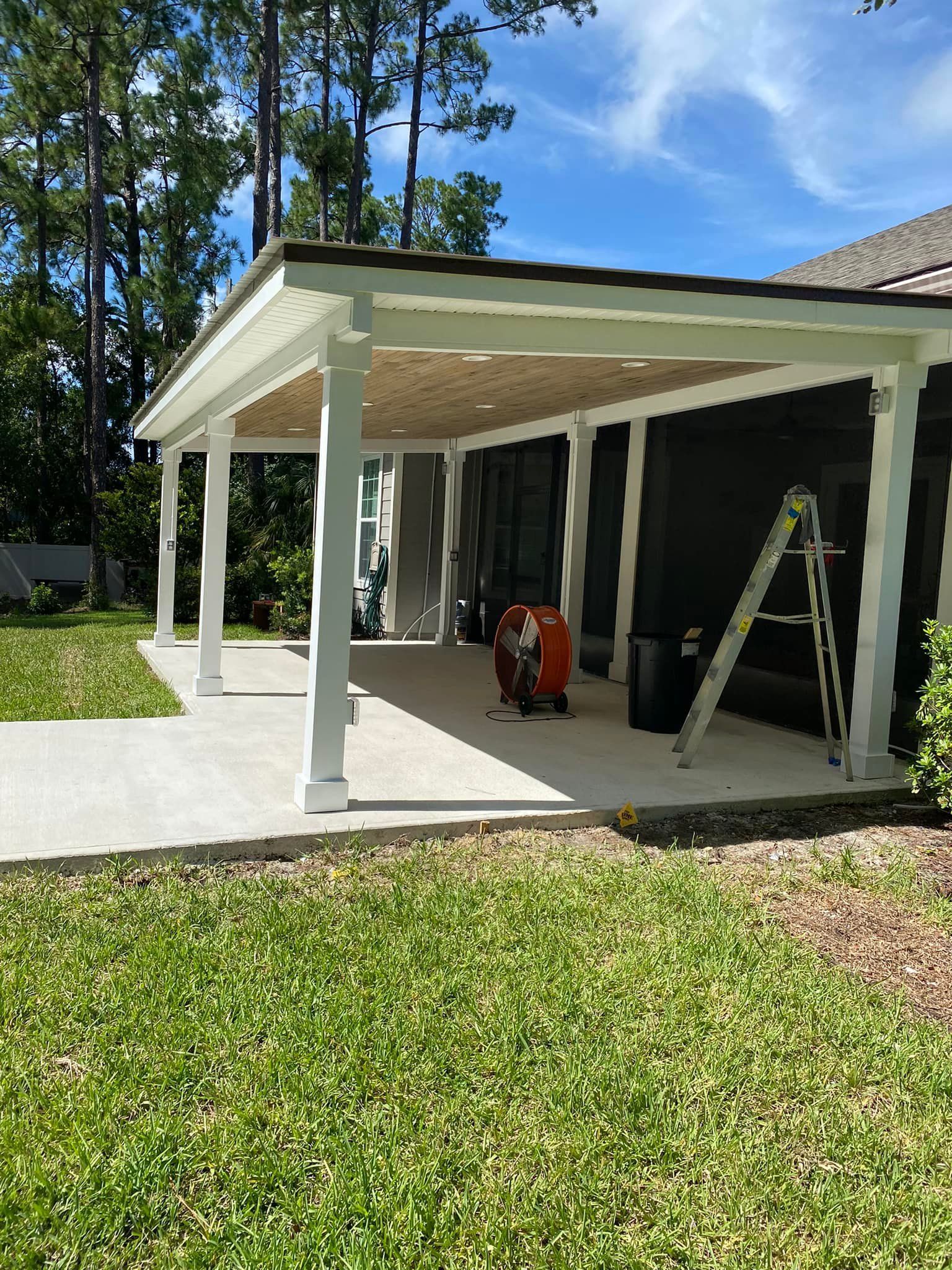 A covered porch with a ladder in the backyard of a house.