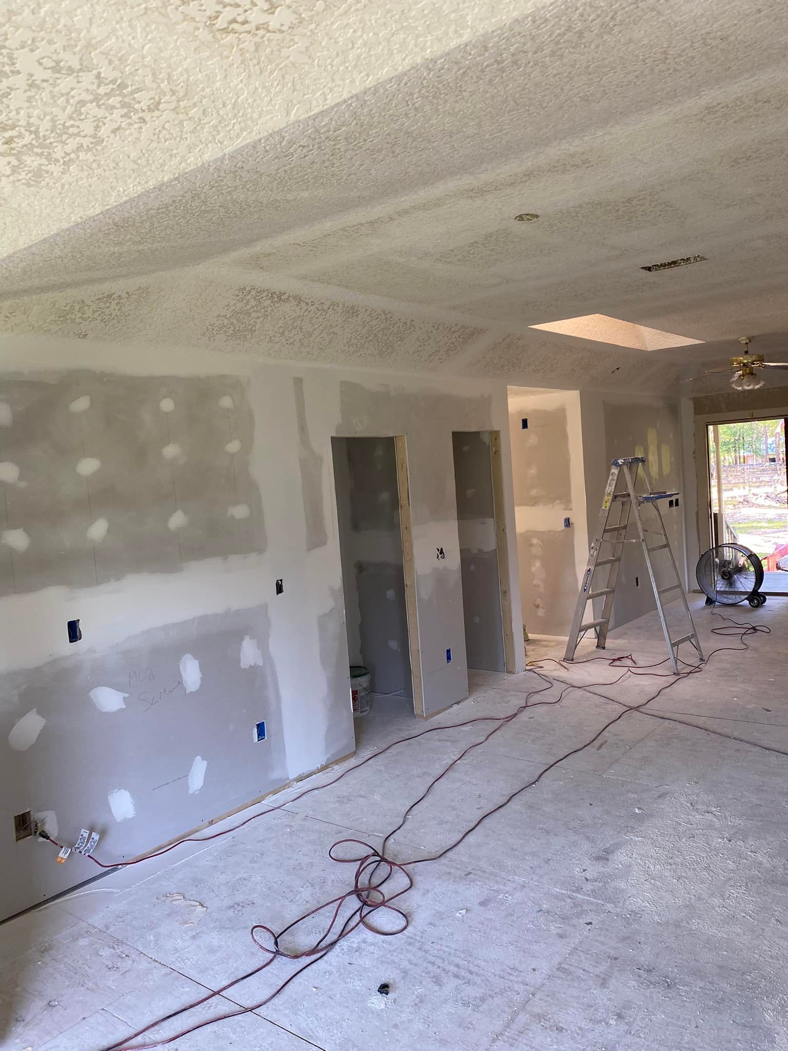 A room that is being remodeled with drywall and a ladder.