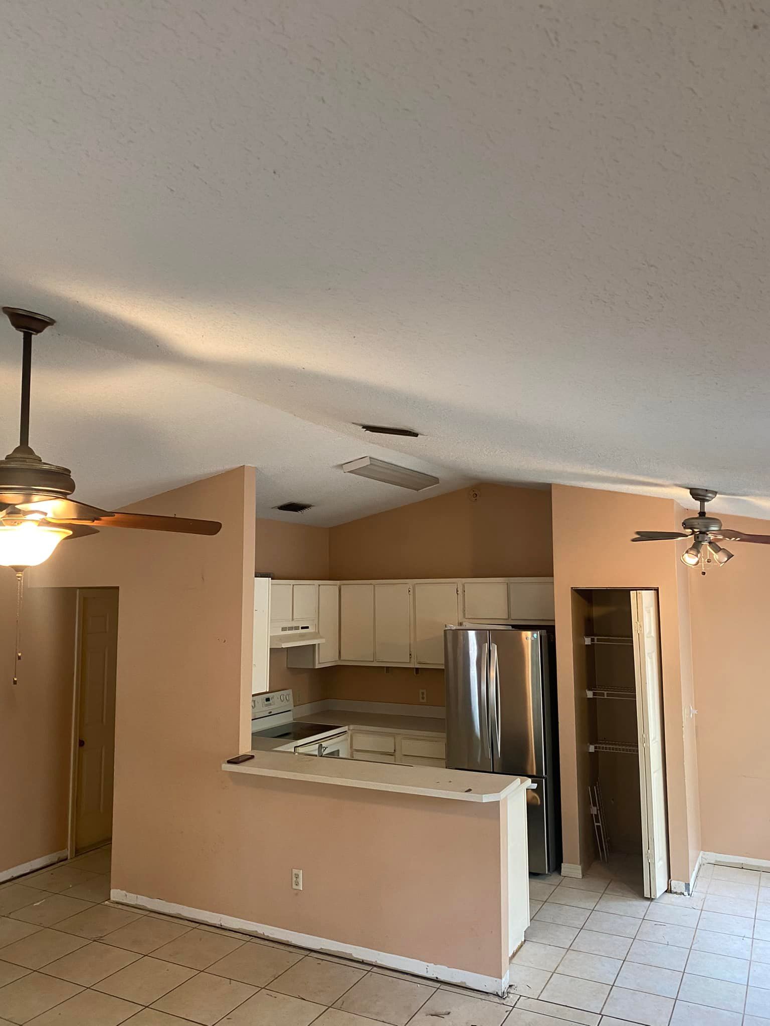 A kitchen with a refrigerator , stove , and ceiling fan.