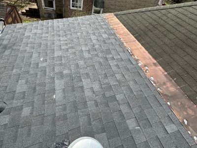 A close up of a roof with shingles and a copper gutter.