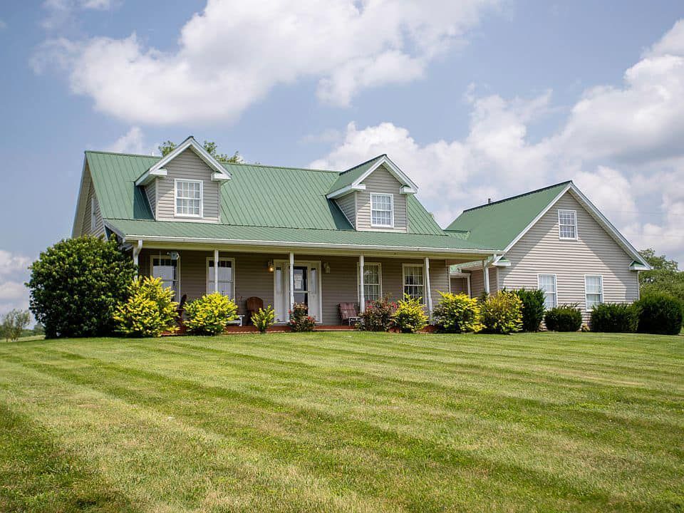 A house with a green roof and a large lawn in front of it
