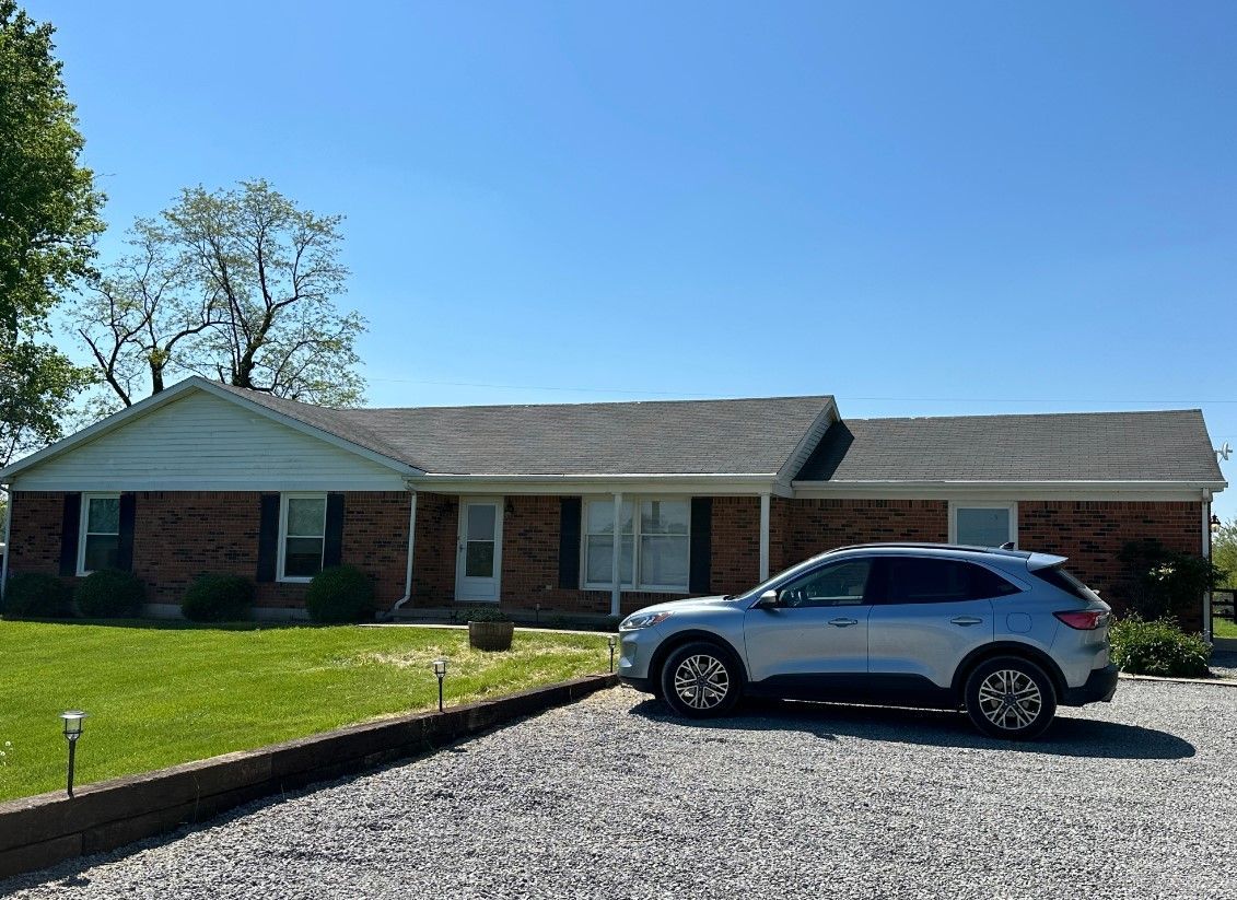 A silver suv is parked in front of a brick house.