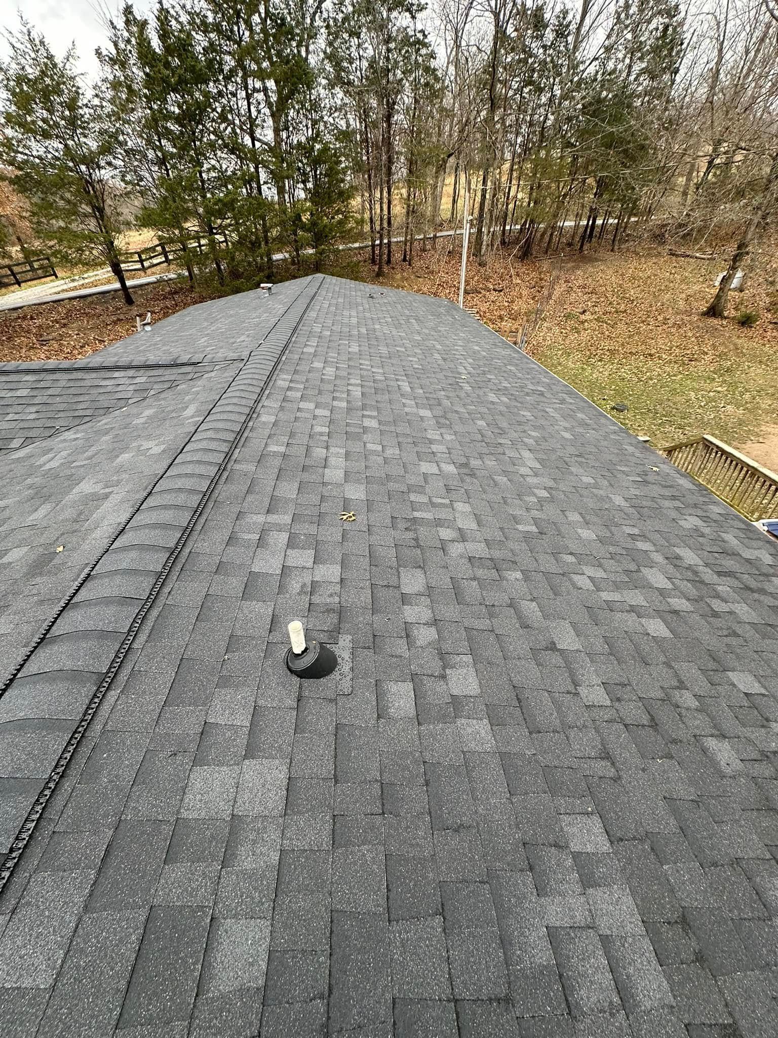 A roof with a lot of shingles on it and trees in the background.