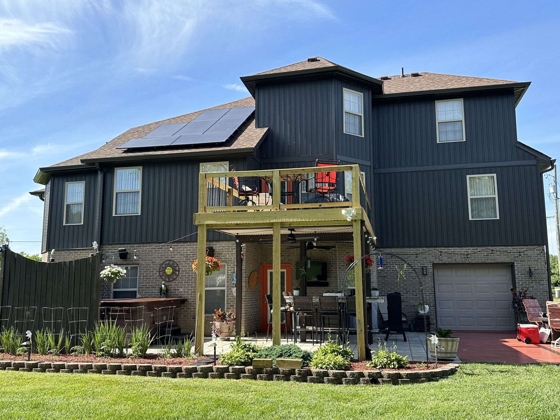 A large house with a large deck and solar panels on the roof.