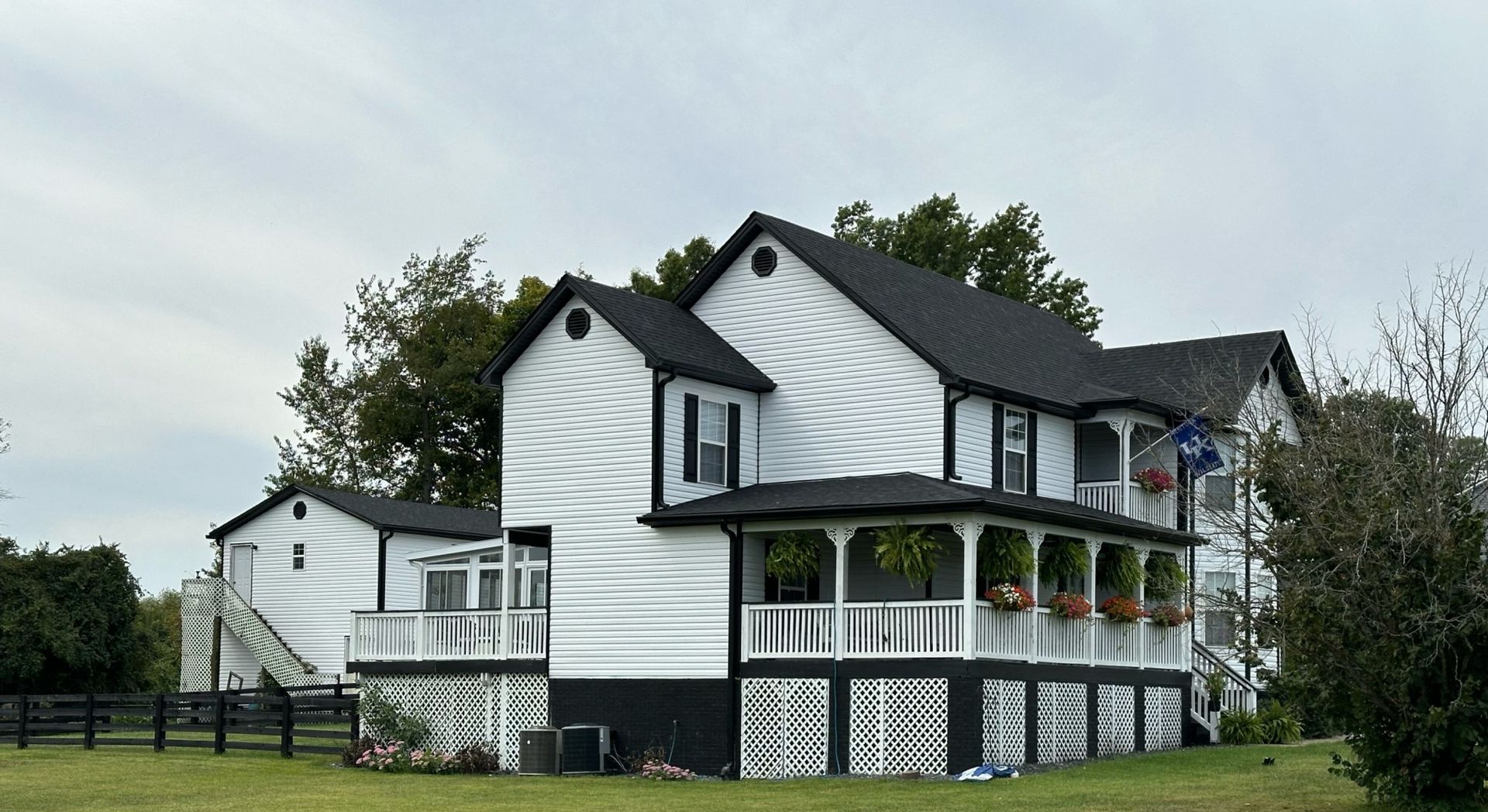 A large white house with a black roof and a large porch