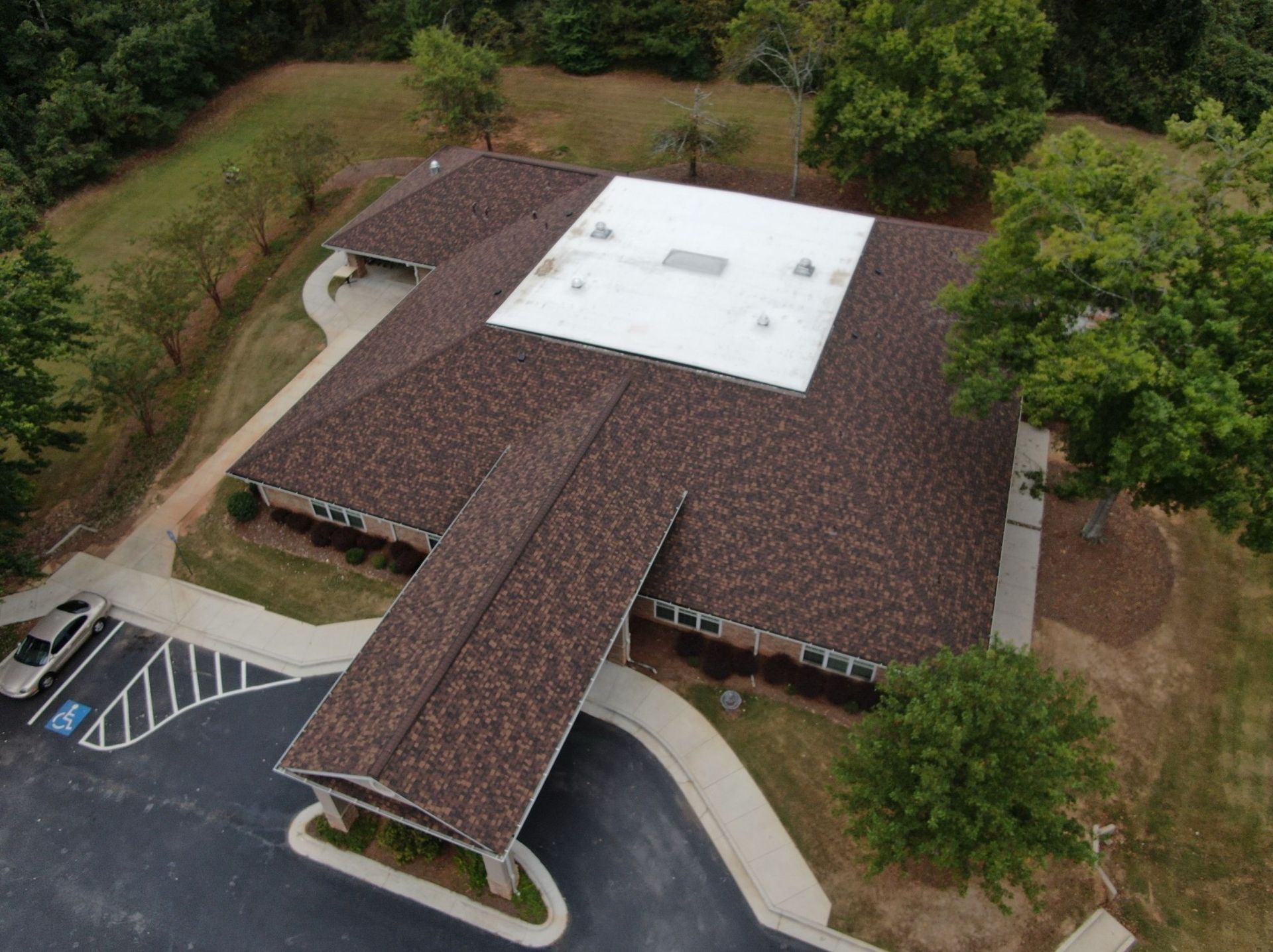 An aerial view of a large building with a white roof surrounded by trees.