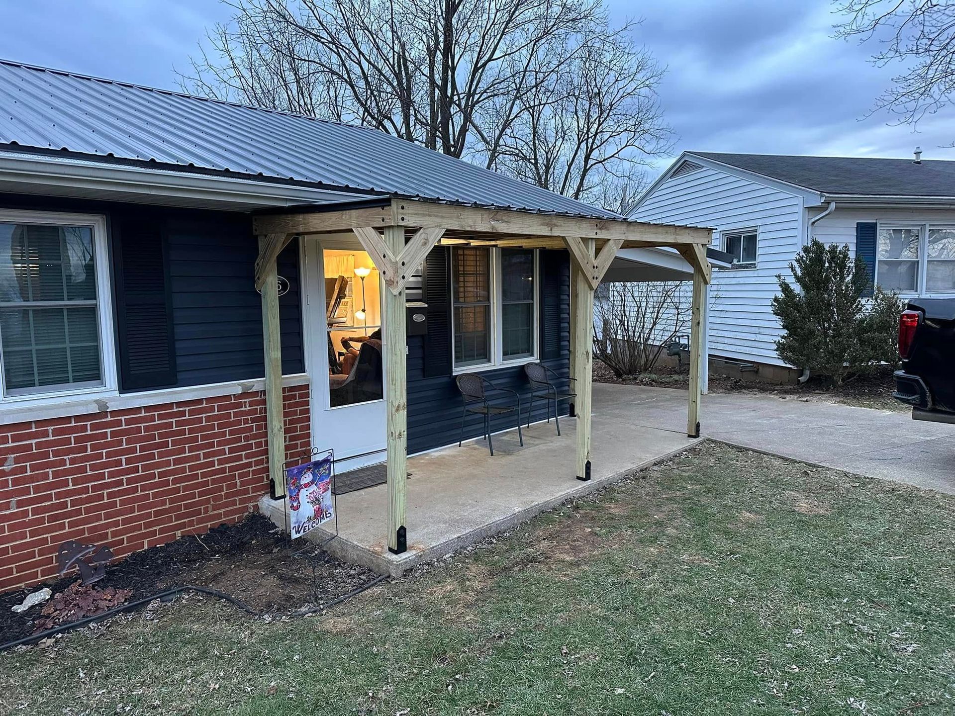 A house with a porch and a truck parked in front of it.