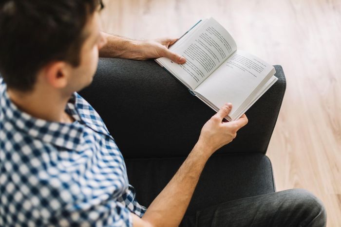 Man Is Sitting on A Couch Reading a Book