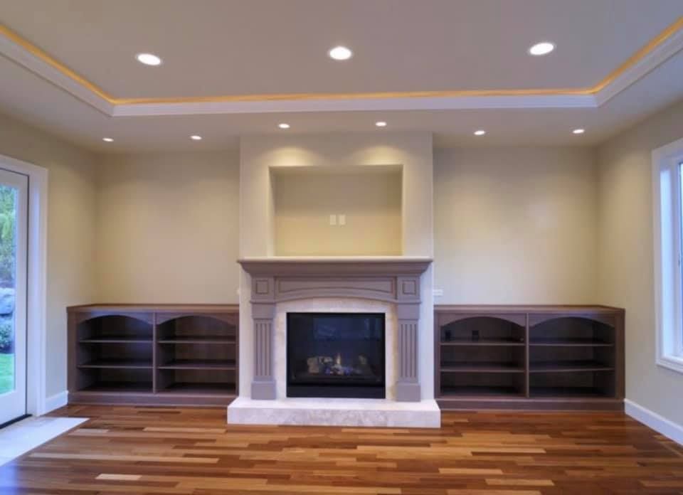 An empty living room with a fireplace and shelves