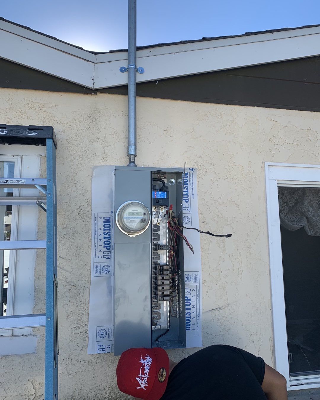 A man in a red hat is working on an electrical box
