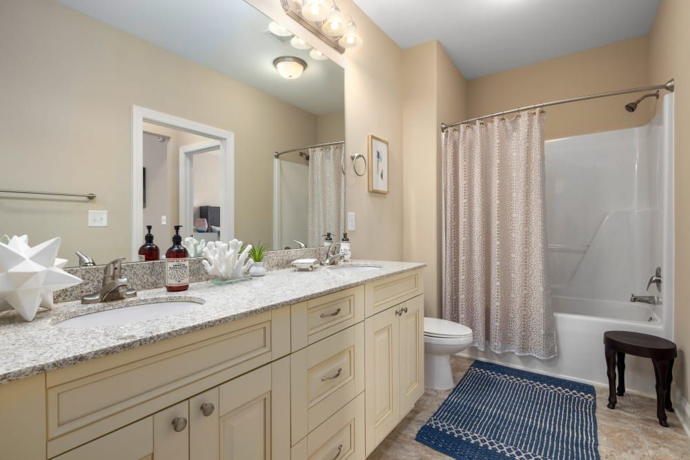 A bathroom with two sinks, a toilet, and a bathtub at Marquis Ellis Crossing in Durham, NC.