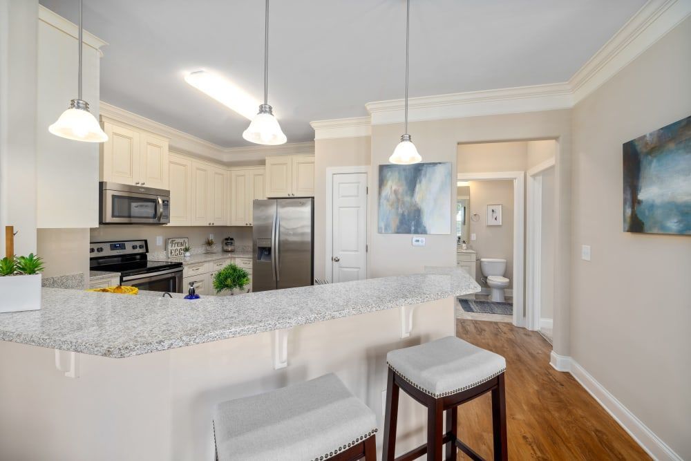 A kitchen with stools, a refrigerator, a microwave, and a sink at Marquis Ellis Crossing in Durham, NC.