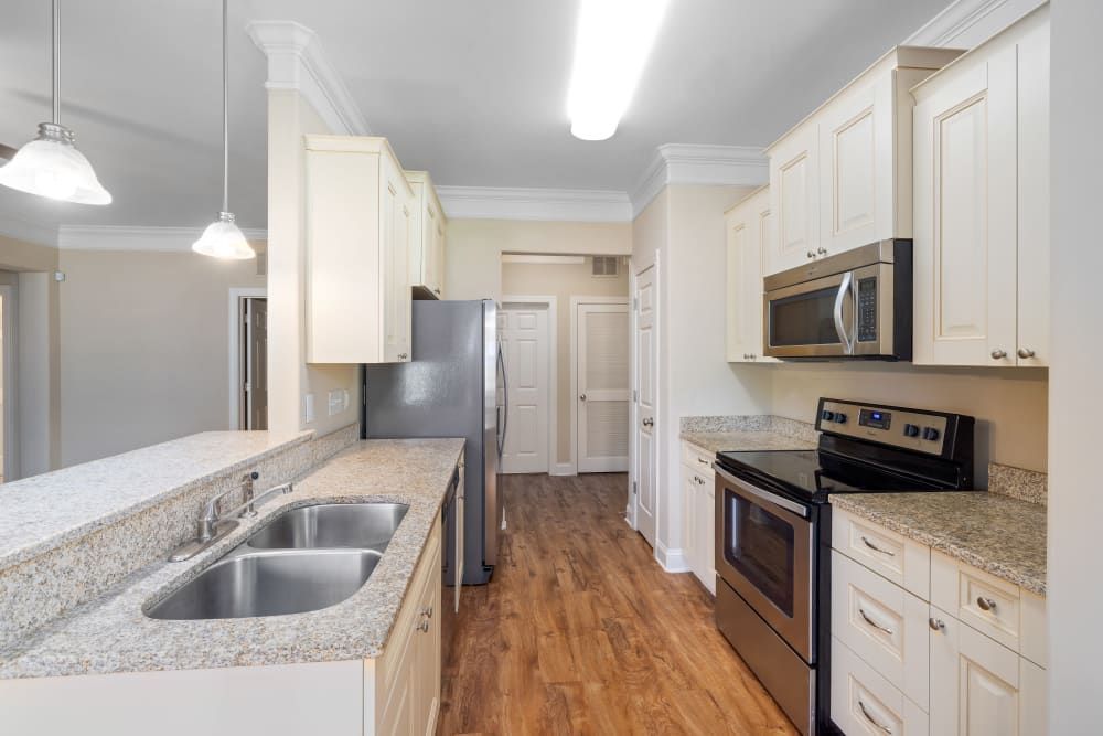 A kitchen with stainless steel appliances and granite counter tops at Marquis Ellis Crossing in Durham, NC.