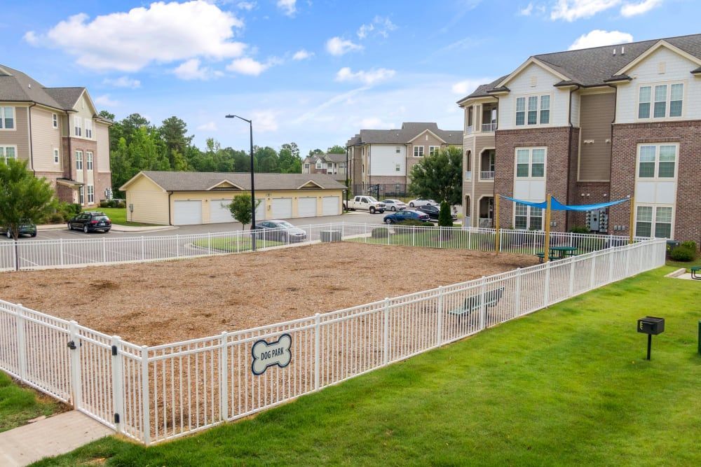A dog park is surrounded by a white fence at Marquis Ellis Crossing in Durham, NC.