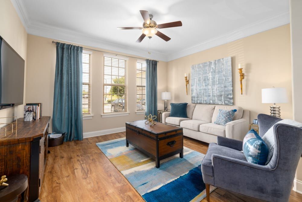 A living room with a couch, chair, coffee table, and television at Marquis Ellis Crossing in Durham, NC.