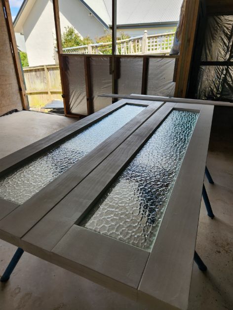 Two Glass Doors Are Sitting on a Wooden Table in a Room — Moss Vale Glass In Bowral, NSW